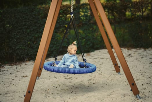 blonde haired girl on the swing