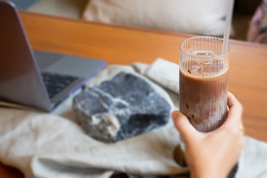 Glass of milk coffee and laptop on the table, stock photo