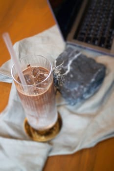Glass of milk coffee and laptop on the table, stock photo