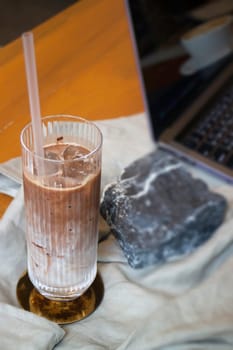 Glass of milk coffee and laptop on the table, stock photo