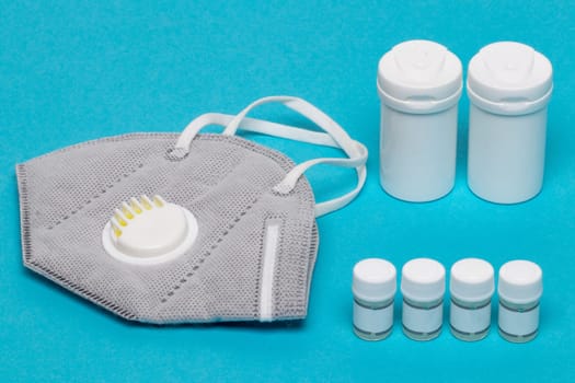 Coronavirus treatment concept. Close-up of a N95 face mask or particle filtering half mask and various medical containers without labeling. Template for a vaccine.