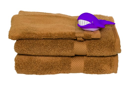 Brown towels isolated. Closeup of a stack or pile of brown soft terry bath towels with funny whale on it isolated on a white background.