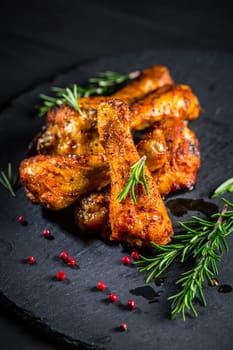 Hot spicy chicken legs with herbs on black background