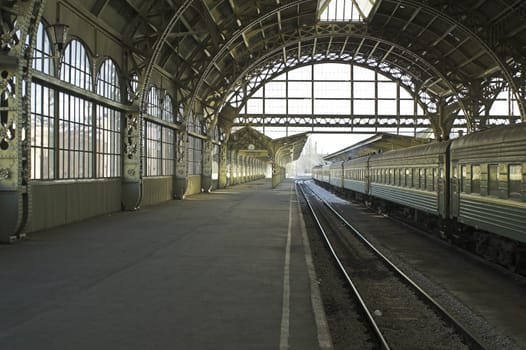 Railroad station platform with a hanging clock and "Have a nice trip"" signboard."