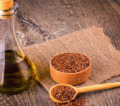 The Brown flax seeds and flaxseed oil on a wooden surface
