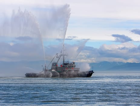 the Floating tug boat is spraying jets of water