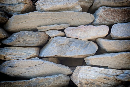 The texture of the stone-brick multi-colored masonry with large cracks and a rough coating
