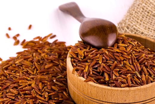 The brown rice, burlap and spoon in a wooden cup on a white dining table