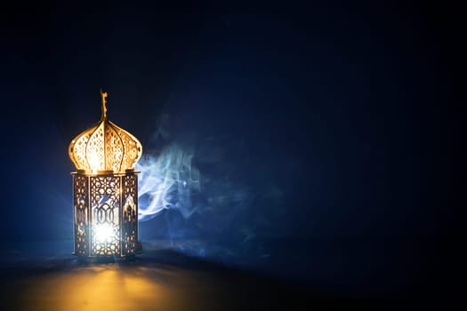 Ornamental Arabic lantern with burning candle glowing at night and glittering golden bokeh lights. Festive greeting card for Muslim holy month Ramadan Kareem.