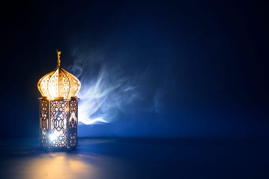 Ornamental Arabic lantern with burning candle glowing at night and glittering golden bokeh lights. Festive greeting card for Muslim holy month Ramadan Kareem.