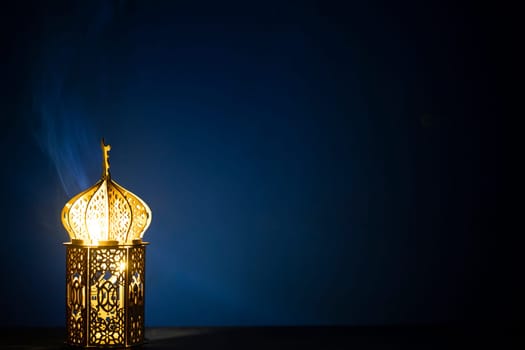 Ornamental Arabic lantern with burning candle glowing at night and glittering golden bokeh lights. Festive greeting card for Muslim holy month Ramadan Kareem.