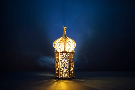 Ornamental Arabic lantern with burning candle glowing at night and glittering golden bokeh lights. Festive greeting card for Muslim holy month Ramadan Kareem.