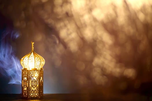 Ornamental Arabic lantern with burning candle glowing at night and glittering golden bokeh lights. Festive greeting card for Muslim holy month Ramadan Kareem.