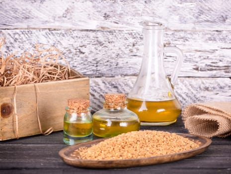 Sesame oil in glass and seeds on lod wooden background