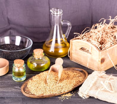 Sesame oil in glass and seeds on lod wooden background