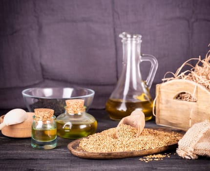 Sesame oil in glass and seeds on lod wooden background