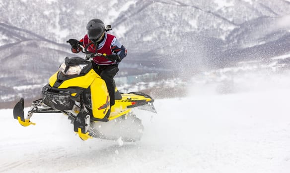 the man is flying on a snowmobile on a background mountains