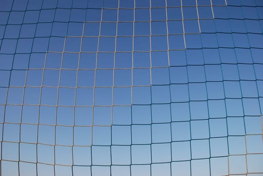 A blue and white goal net for ball sports such soccer,handball and volleyball. In the background the blue sky.