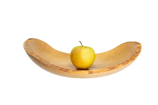 Side view of a flat wooden bowl with an apple in the middle isolated on white