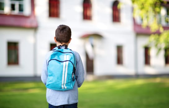 Boy with rucksack infront of a school building. Child with a backpack