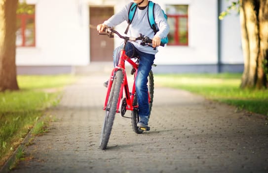 child on a bicycle at asphalt road in early morning. Boy on bike near school
