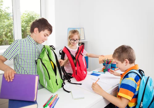 Children sitting in the room with books. Pupils writing at school