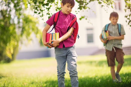 Children with rucksacks standing in the park near school. Pupils with books and backpacks outdoors