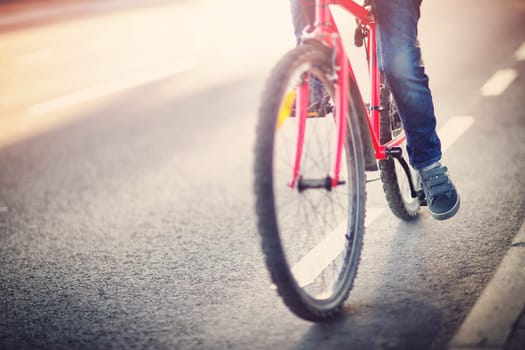 child on a bicycle at asphalt road in early morning. Boy on bike in the city