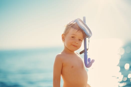 three years old boy playing at the beach with swimming mask. Child on family vacations at sea