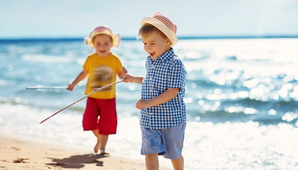 Boy and girl playing on the beach on summer holidays. Children in nature with beautiful sea, sand and blue sky. Happy kids on vacations at seaside running in the water
