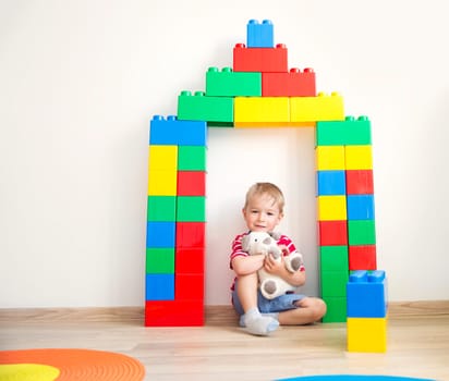 happy three years old child sitting on the floor with toys. Pretty little boy palying with cubes at home