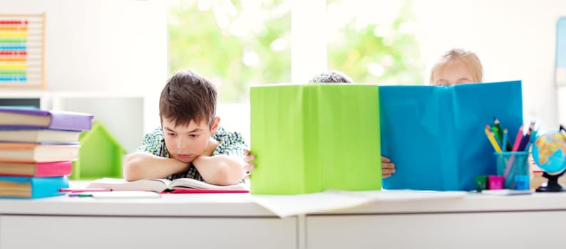 Children sitting in the room with books. Pupils reading at school