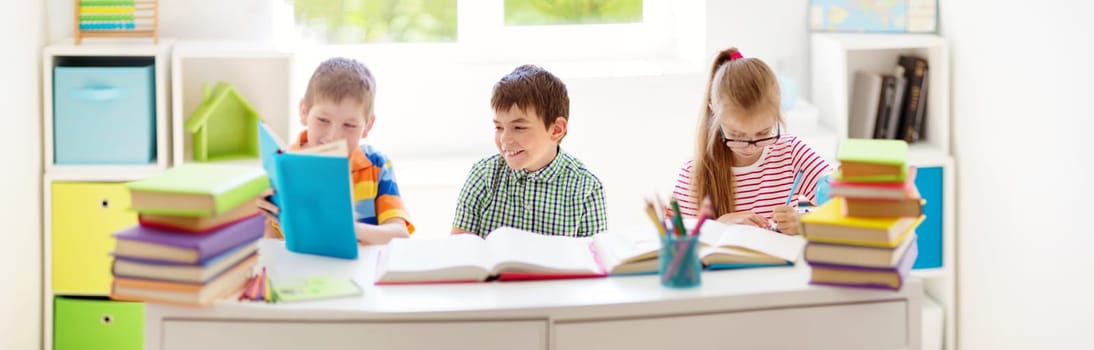 Children sitting in the room with books. Pupils reading at school
