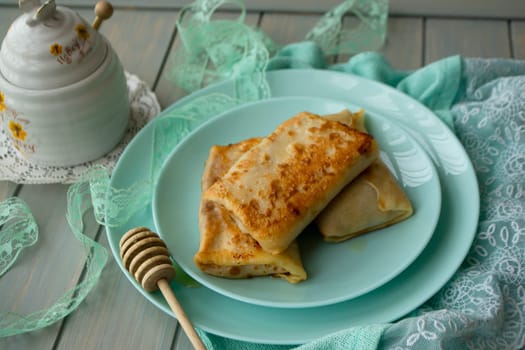 Rolls of pancakes stuffed with jam and apple on teal plate