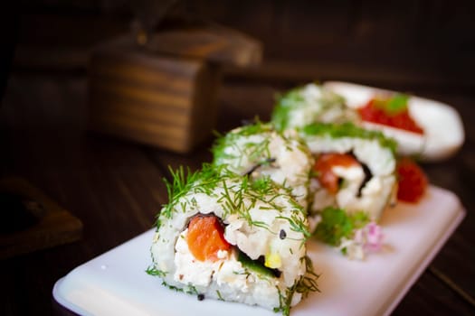 Green maki sushi. Roll made of smoked salmon, cream cheese and cucumber inside.