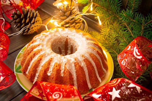 Traditional homemade christmas cake holiday dessert with new year tree decorations frame on vintage dark wooden table.