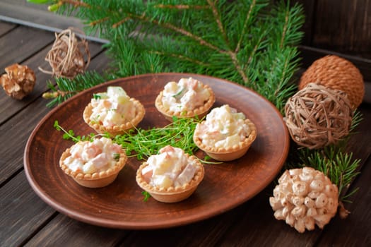 big brown plate, standing on the wooden table and served with a tartlets with olivier salad and piece