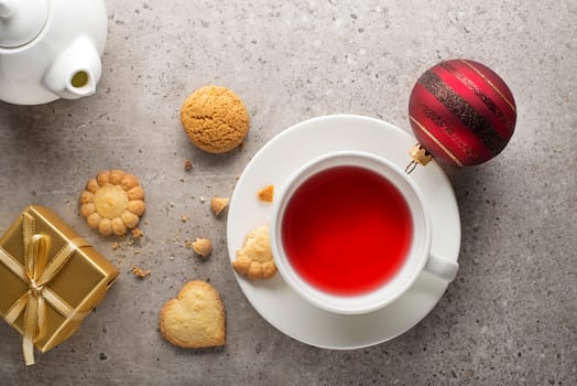 Winter hot tea cup with cookies on grey table. Top view, Christmas decorations, copy space.