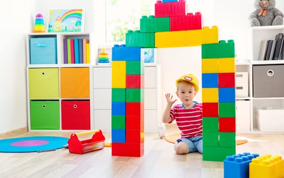 happy three years old child sitting on the floor with toys. Pretty little boy palying with cubes at home