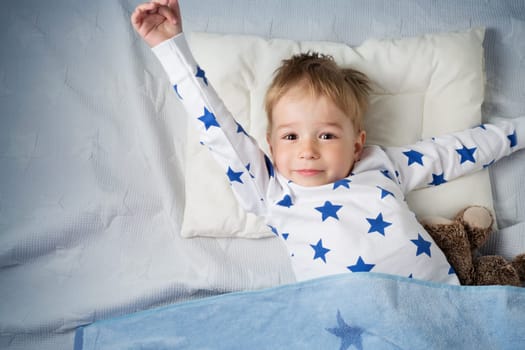 three years old child sleeping in bed on pillow with a teddy bear