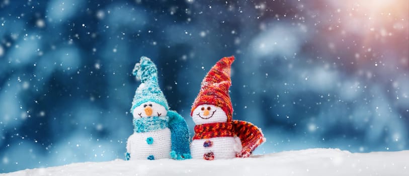 little knitted snowmans on soft snow on blue background