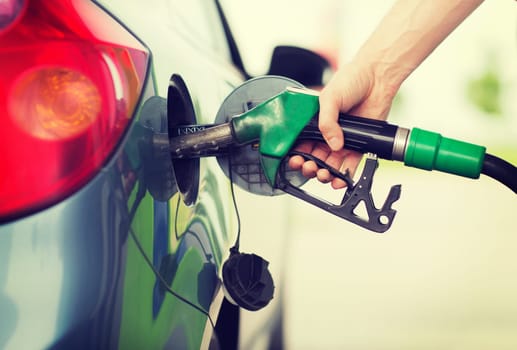 transportation and ownership concept - man pumping gasoline fuel in car at gas station