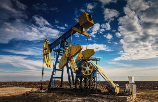 Operating oil well profiled on dramatic cloudy sky