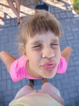 Mischievous girl grimaces and shows a vile muzzle with a tongue