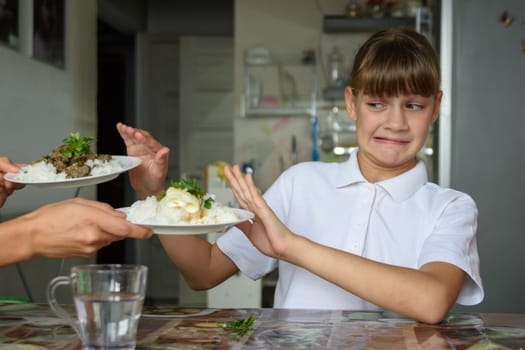 The girl at the dinner table refuses the food offered