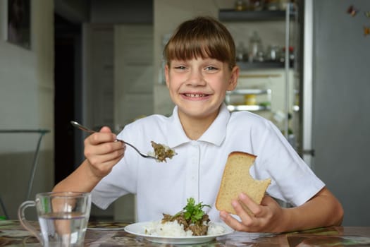 Happy girl happily eats the second dish and looks into the frame with a cute smile
