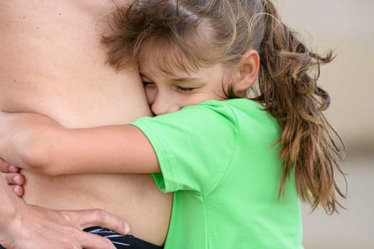 Happy girl hugs the belly of an adult