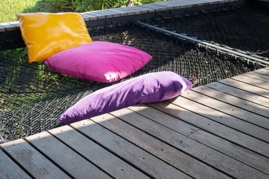 Colorful pillows on net seat among nature, stock photo