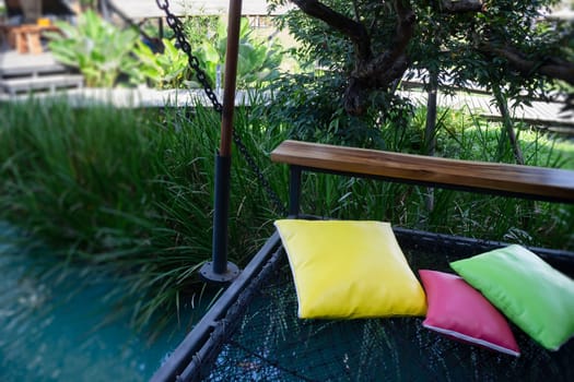 Colorful pillows on net seat among nature, stock photo