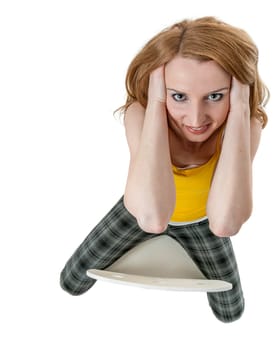 Wide angle extremely high full length view of a young blonde woman sitting astride a chair with hands left and right in her hair looking friendly at the camera isolated on white.